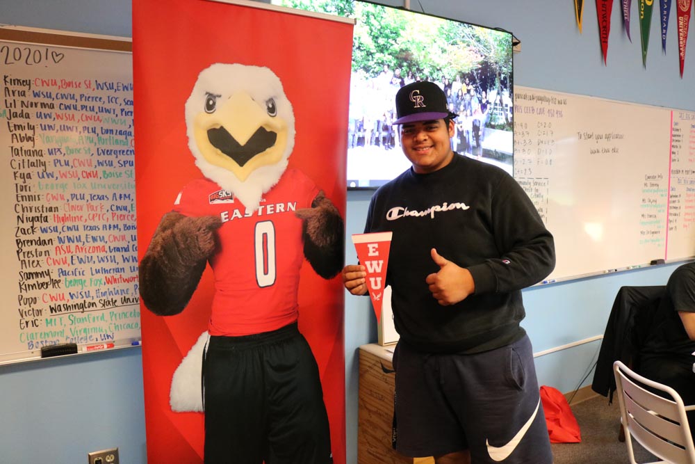 Student in front of EWU banner with thumbs up.